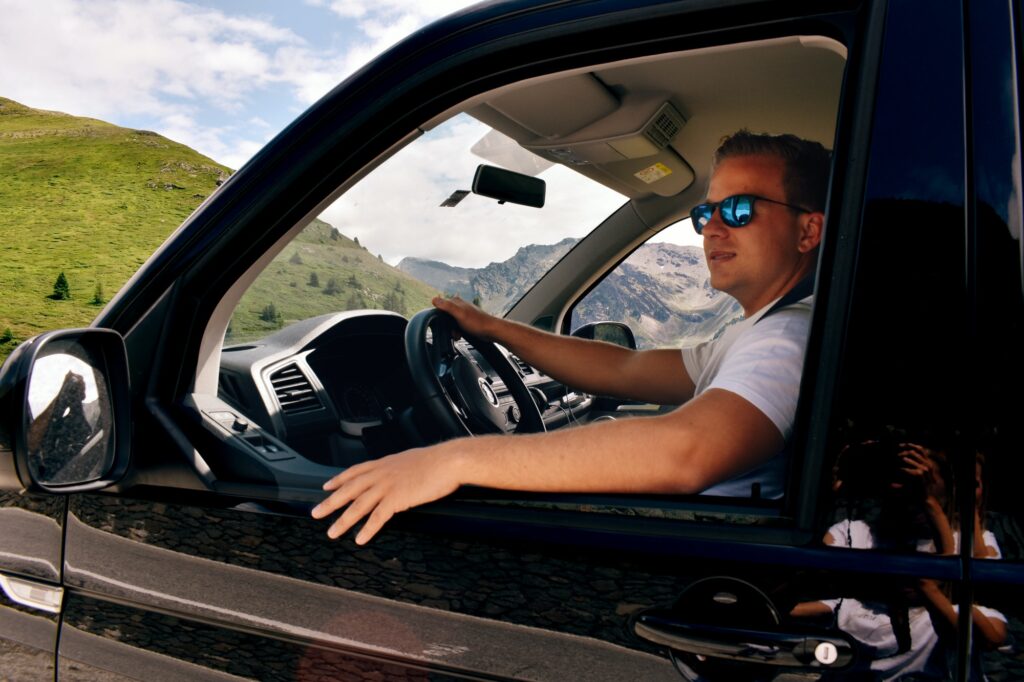 Portrait of man driving black van in the mountains